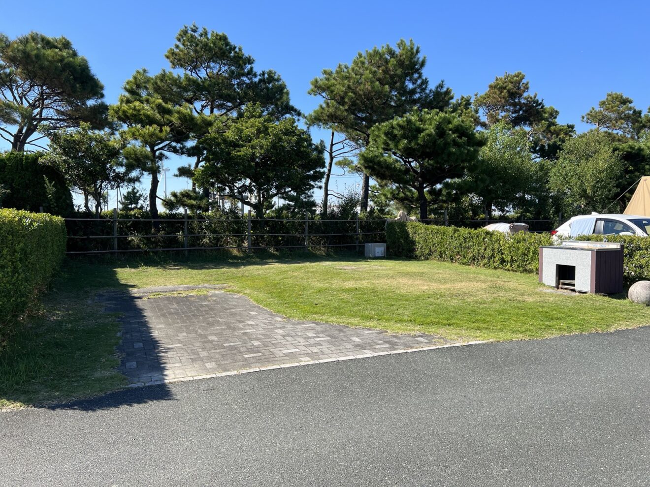 舗装された駐車部分と芝地、生垣、右側の流し台
